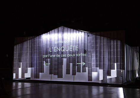 photo de la façade du décor du spectacle l'enquête composé de feuilles de papier rétro éclairée